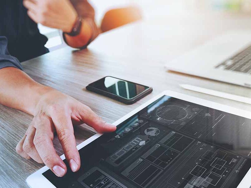 Man working at desk with tablet, smartphone and laptop